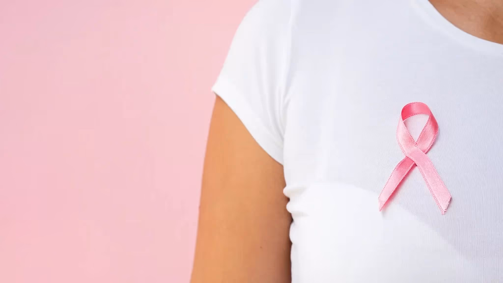 Laço rosa de conscientização sobre o câncer de mama preso a uma camiseta branca