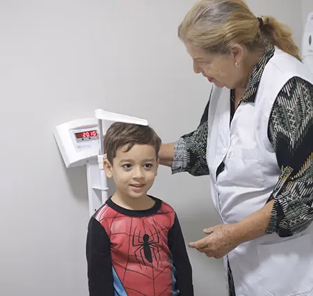 Pediatra da Med Anchieta medindo a altura de uma criança durante a consulta